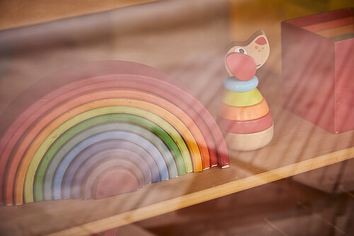 Bunter Holz-Regenbogen und -Figur im Regal